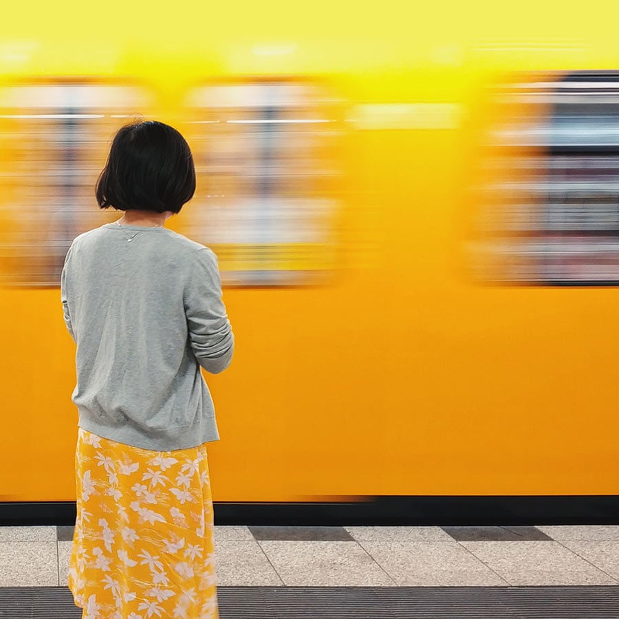 A woman standing in front of public transport, as urban mobility is transformed with digital payments